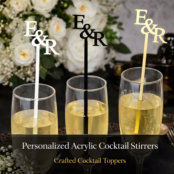 Three glasses with personalized cocktail stirrers featuring 'E&R' against a floral background.