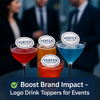 Four colorful cocktails with branded edible drink toppers featuring the Consulting logo, displayed on a high-top table at a corporate event, with blurred business professionals networking in the background.